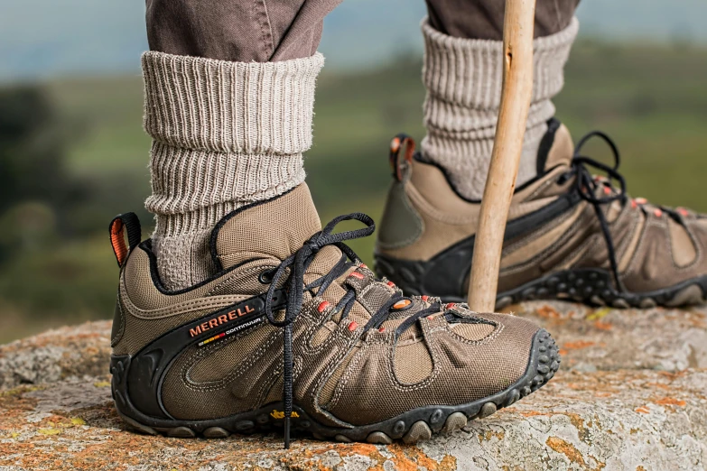 a person standing on a rock with a walking stick, battle shoes, socks, fossil, wolverine