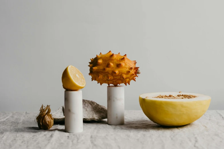 a close up of a fruit on a table, inspired by Sarah Lucas, unsplash, visual art, yellow gemstones spikes, white marble sculpture, two arms that have sharp claws, datura