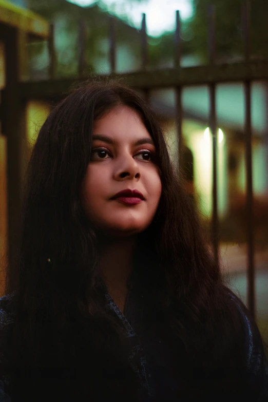 a woman with long hair standing in front of a fence, an album cover, inspired by Elsa Bleda, pexels contest winner, mixed-race woman, night view, dafne keen, headshot profile picture