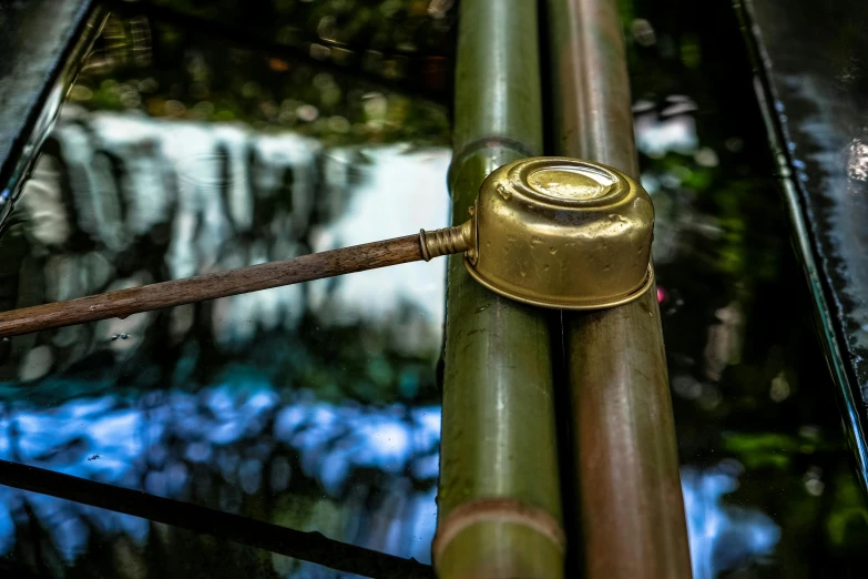 a close up of a bamboo pole with a water fall in the background, by Jan Tengnagel, pexels contest winner, brass plated, watering can, reflection echo, thumbnail