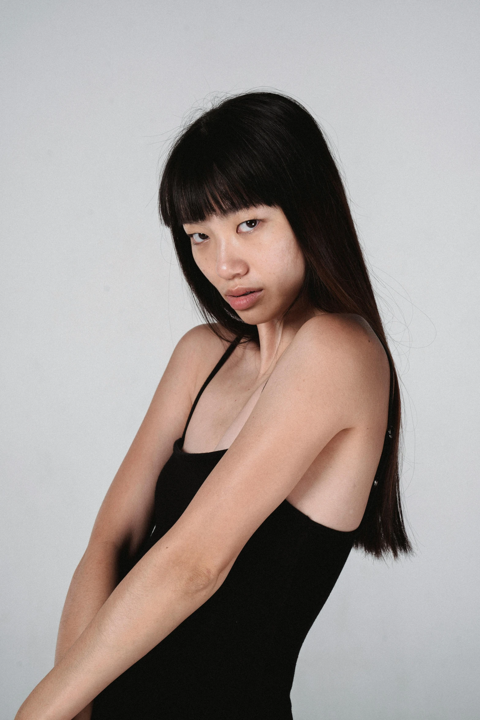 a woman in a black dress posing for a picture, inspired by Wang E, reddit, wearing a tanktop, studio portrait photo, (((luke chueh))), bangs