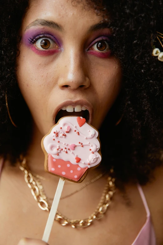 a close up of a person holding a lollipop, inspired by Martin Schoeller, renaissance, eating cakes, afro, charli xcx, cookies