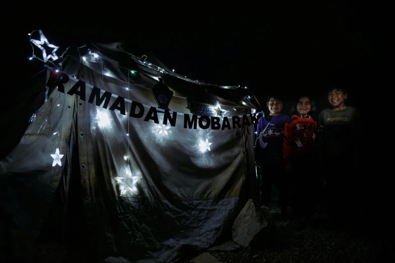 a group of people standing in front of a tent, an album cover, by Maryam Hashemi, lights in the dark, guardian project, nomads, can basdogan