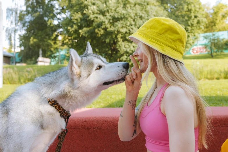 a woman in a yellow hat petting a husky dog, pexels contest winner, ava max, summer day, 1 4 9 3, snacks