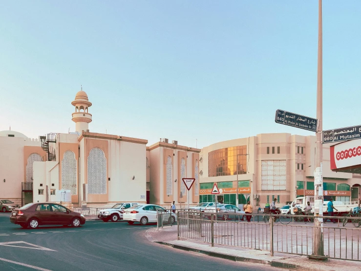 a red car driving down a street next to a tall building, by Ahmed Yacoubi, pexels contest winner, hyperrealism, mosque, sunfaded, shopping mall, panoramic shot