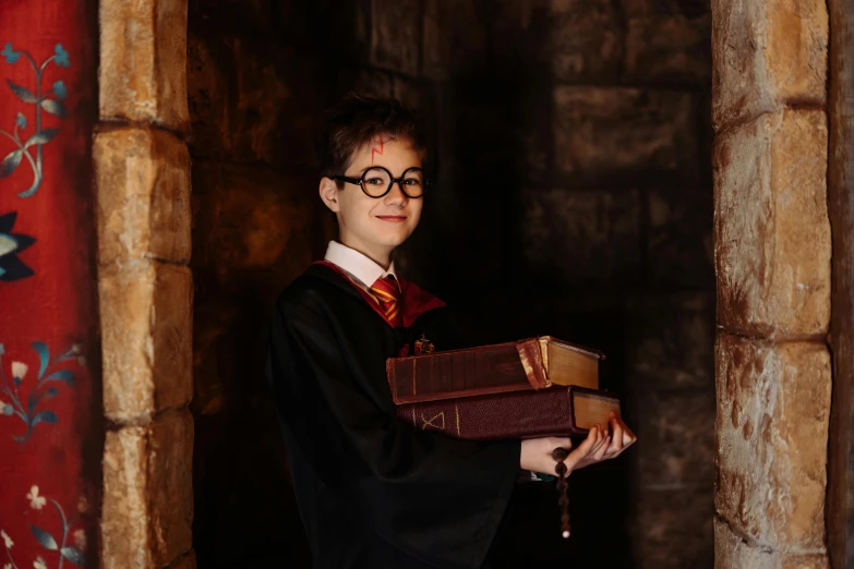 a young boy dressed as harry potter holding two books, a portrait, pexels contest winner, hogwarts castle, tech robes, promotional photoshoot, avatar image