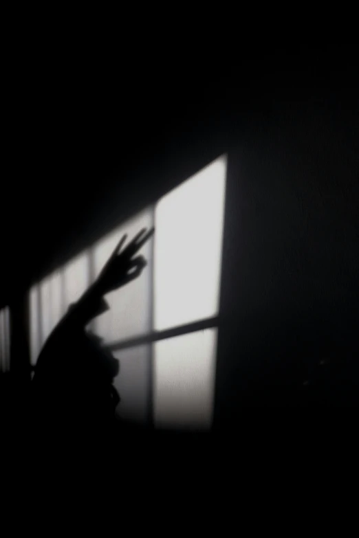 a person standing in front of a window in the dark, a picture, 2 5 6 x 2 5 6, raised hand, shadowcreature, wallpaperflare