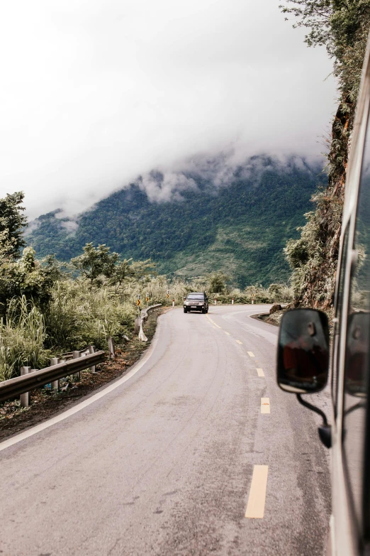 a car that is sitting on the side of a road, by Tom Bonson, trending on unsplash, jungles of vietnam beautiful, at a volcano, 🚿🗝📝