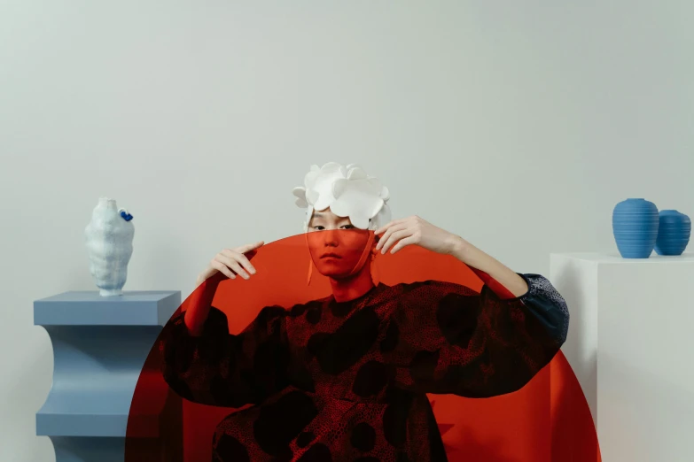 a woman sitting on top of a red chair, a surrealist sculpture, inspired by Gao Cen, pexels contest winner, conceptual art, frosting on head and shoulders, margiela campaign, on a couch, eero aarnio