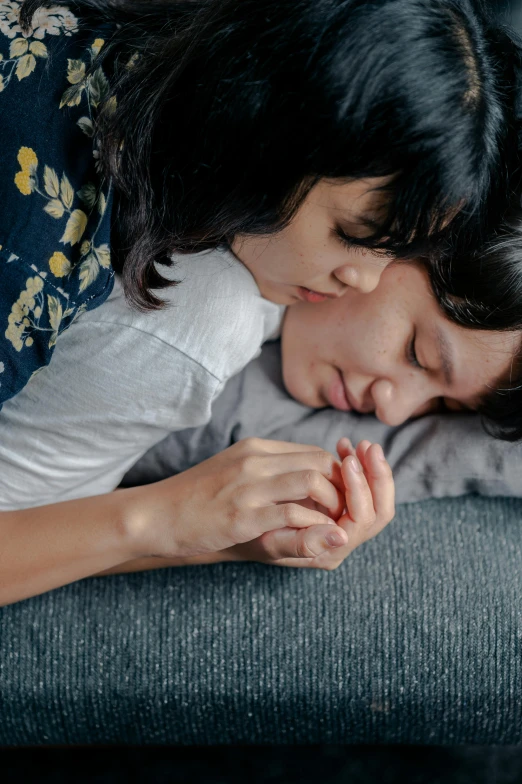 a couple of people laying on top of a couch, trending on pexels, romanticism, hands shielding face, asian female, lesbian, praying