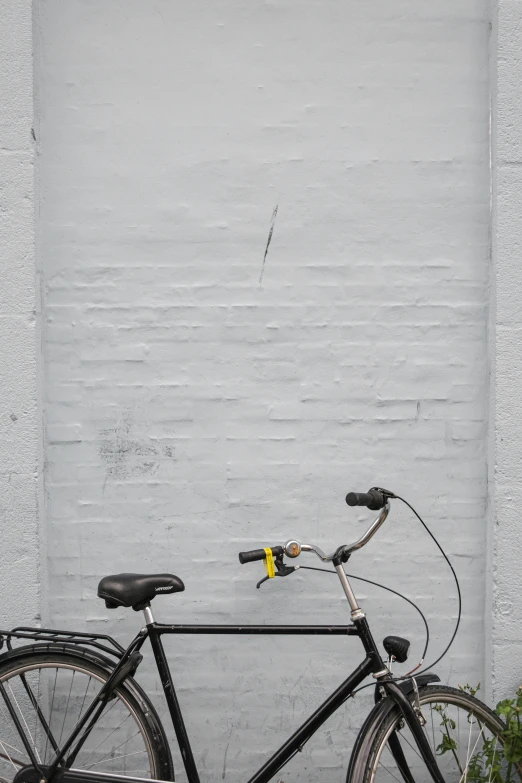 a black bicycle parked against a white brick wall, by Sven Erixson, postminimalism, black and yellow, broken down grey wall, 2019 trending photo, wires and lights