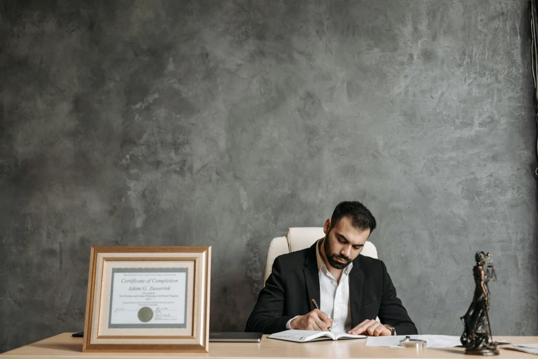 a man sitting at a desk writing on a piece of paper, a picture, kurdish lawyer, high-quality photo, thumbnail, high quality image