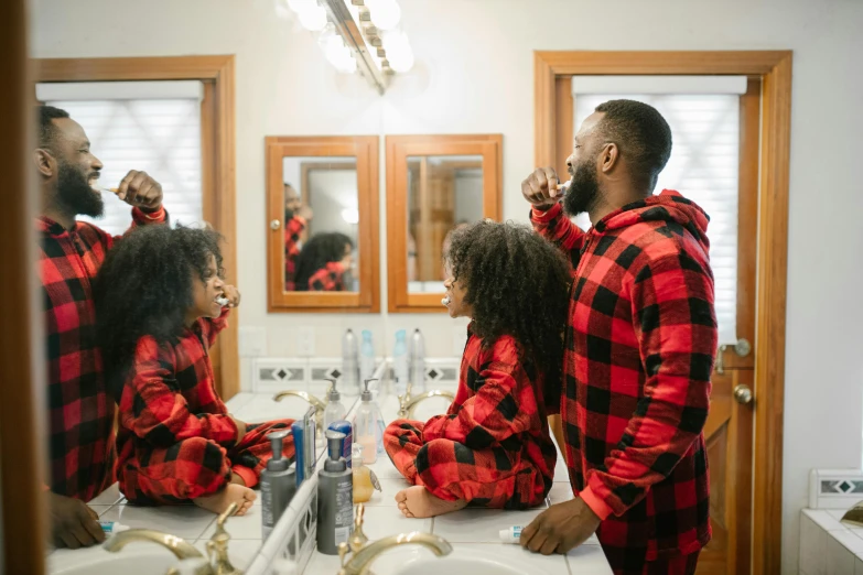 a man brushing his teeth in front of a mirror, by Julia Pishtar, pexels contest winner, happening, fatherly, wearing pajamas, african canadian, families playing