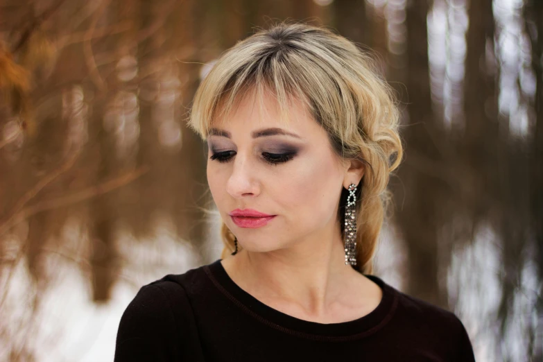 a woman that is standing in the snow, an album cover, inspired by Elina Karimova, trending on pixabay, hurufiyya, long earrings, face portrait of an elegant, evening makeup, 40 years old women