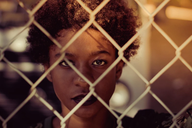 a close up of a person behind a fence, inspired by Gordon Parks, trending on pexels, afrofuturism, portrait rugged girl, stranger things character, brown skinned, medium format. soft light