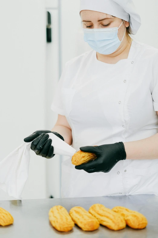 a woman in a white shirt and black gloves holding a bag of doughnuts, pexels, surgical gown and scrubs on, clean medical environment, profile image, black