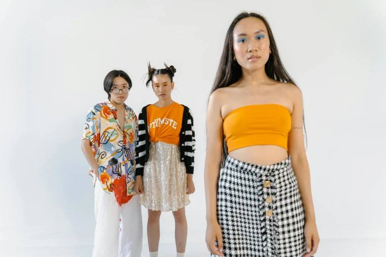 a group of young women standing next to each other, an album cover, trending on pexels, happening, orange halter top, creativity in fashion design, half asian, patterned clothing