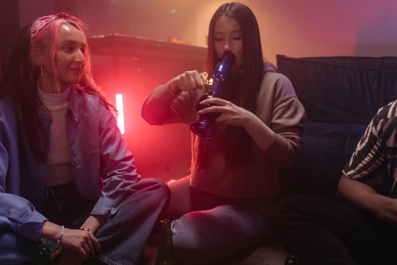 a group of people sitting on top of a couch, smoking a magical bong, low saturated red and blue light, woman holding another woman, led gaming
