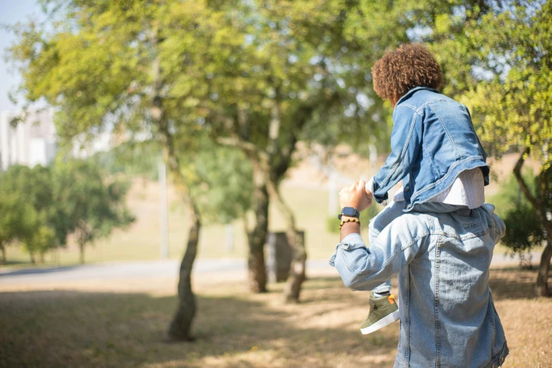 a woman holding a child up in the air, pexels, figuration libre, wearing double denim, walking at the park, a man wearing a backpack, environmental shot