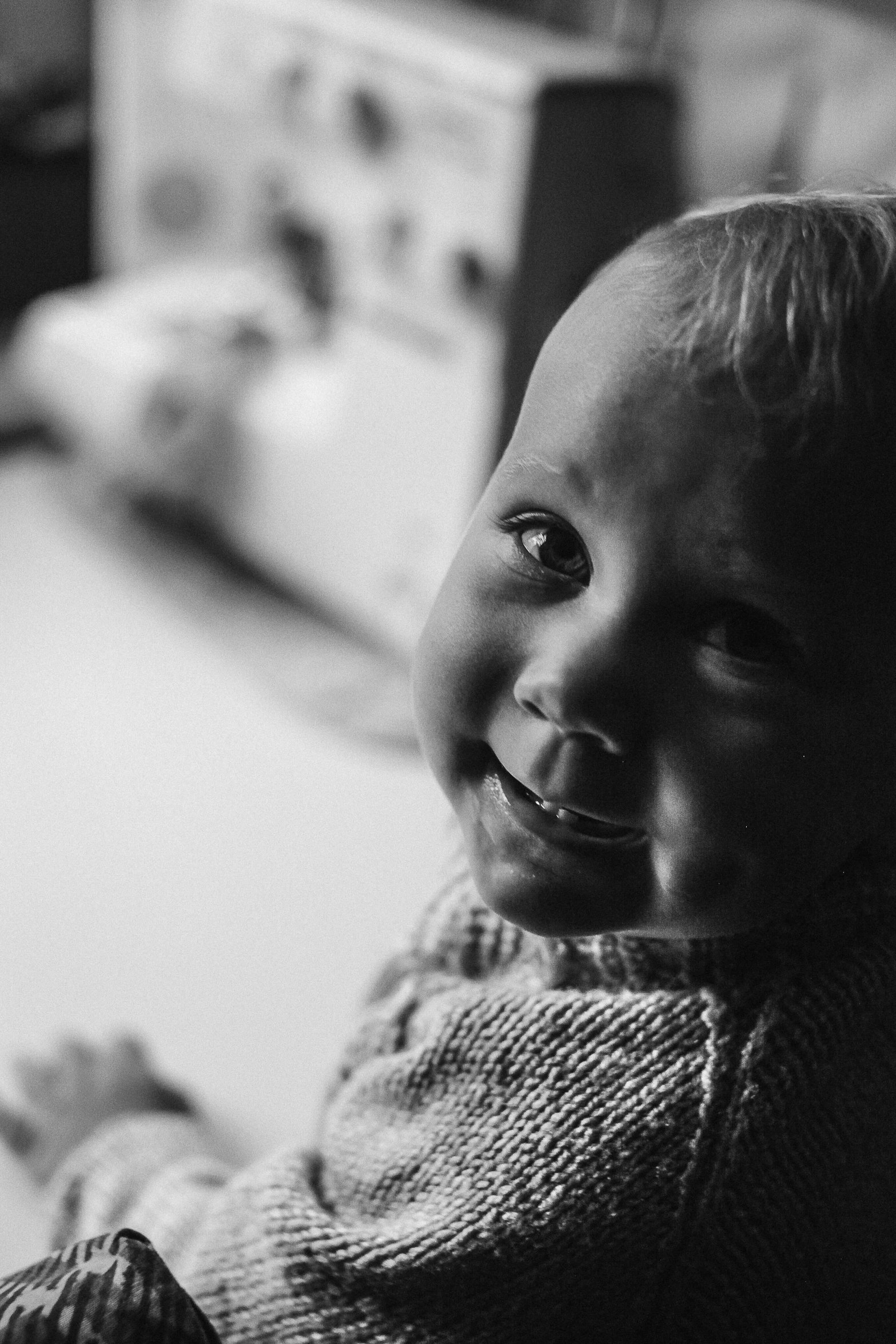 a black and white photo of a baby smiling, by Lee Loughridge, pexels contest winner, portrait of a small character, over his shoulder, smiling maniacally, warm friendly face