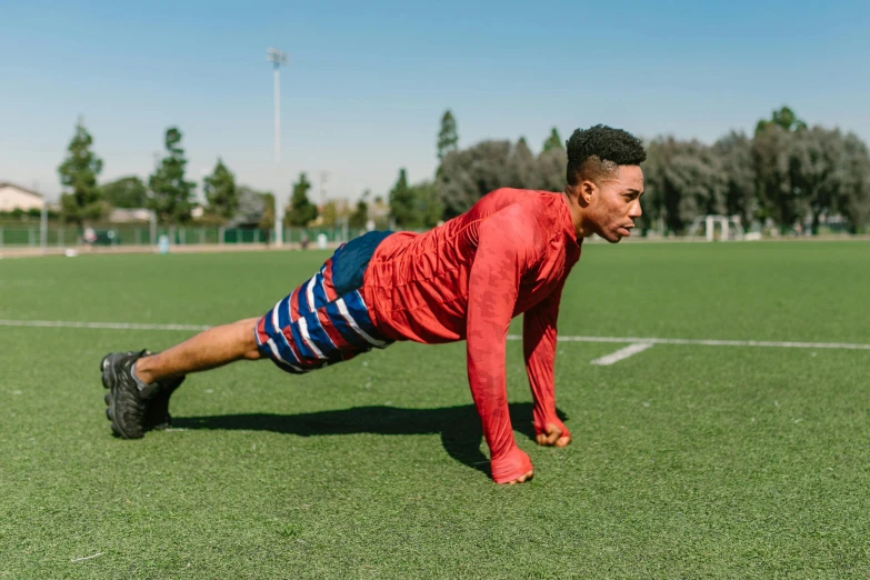 a man doing push ups on a soccer field, by Austin English, pexels contest winner, red and blue garments, alexis franklin, profile image, thumbnail