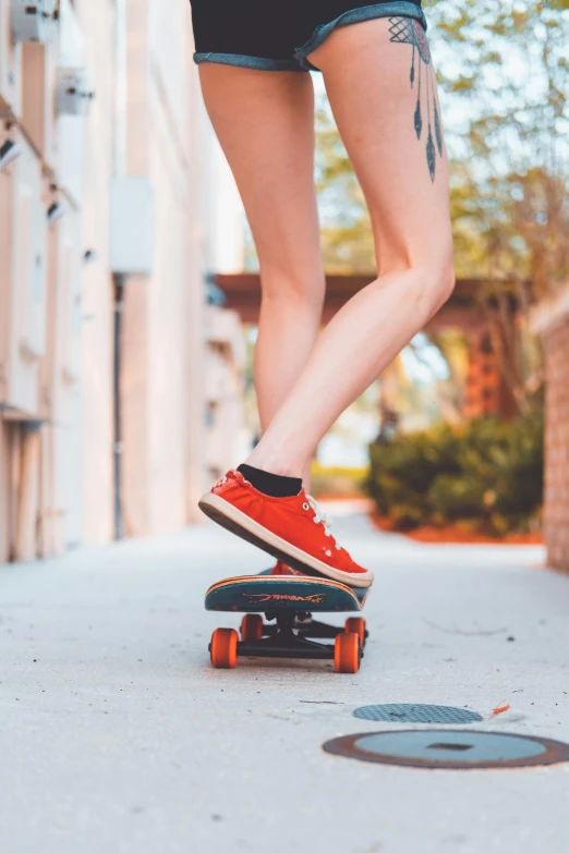 a woman riding a skateboard down a sidewalk, unsplash contest winner, wearing red shorts, gum rubber outsole, red and orange colored, young teen