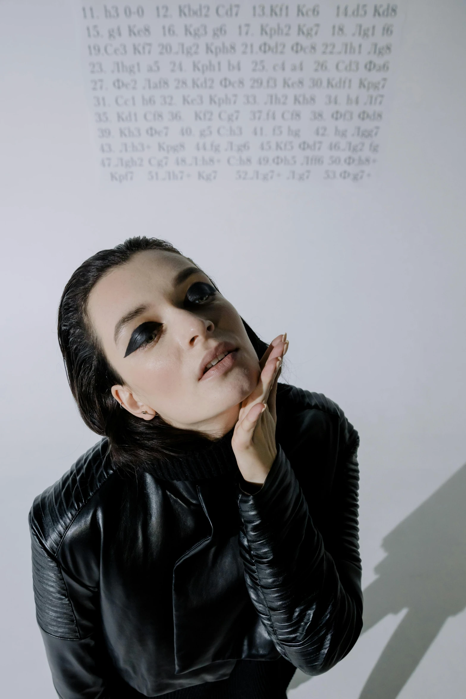 a woman in a black leather jacket smoking a cigarette, an album cover, unsplash, antipodeans, anya taylor-joy, black hair and large eyes, in front of white back drop, in front of a carved screen