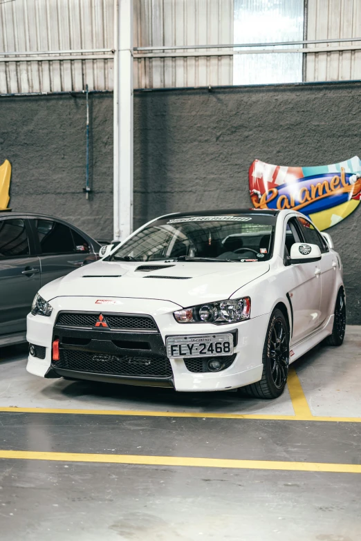 a couple of cars parked next to each other, by An Gyeon, white wall coloured workshop, samurai vinyl wrap, low quality photo, rally car