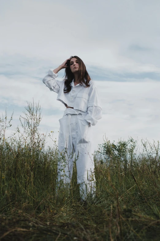 a woman standing on top of a lush green field, an album cover, inspired by Elsa Bleda, pexels contest winner, white trendy clothes, tracksuit, white and silver, model pose