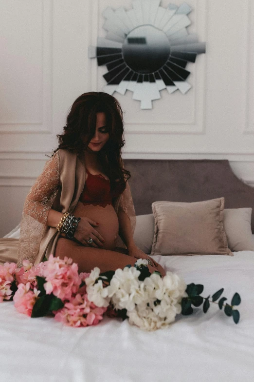 a pregnant woman sitting on a bed surrounded by flowers, pexels contest winner, red brown and grey color scheme, instagram post, brunette, mother