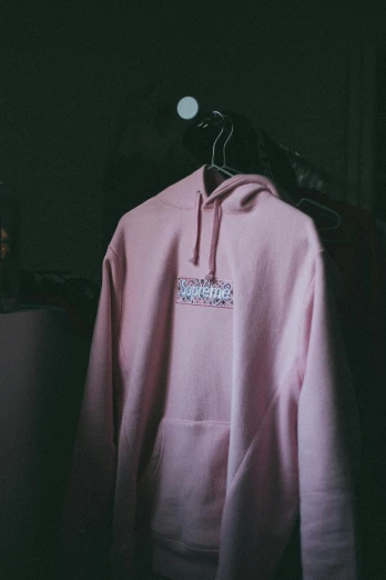 a pink hoodie on a hanger in a dark room, inspired by Elsa Bleda, unsplash, happening, mrbeast, low quality photo, embroidered robes, closeup!!!!!