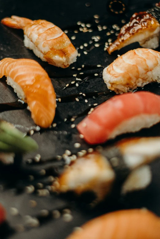 a bunch of sushi sitting on top of a black plate, inspired by Nishida Shun'ei, trending on unsplash, ukiyo-e, thumbnail, prawn, rays, brown