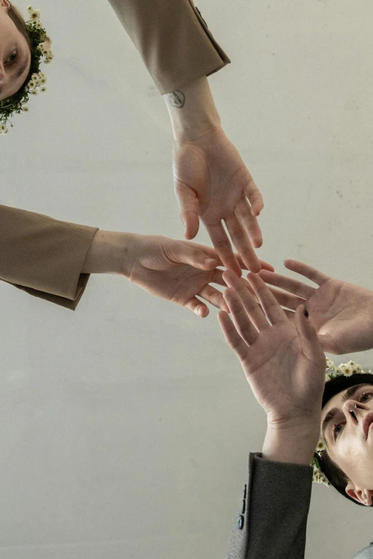 a group of people putting their hands together, an album cover, inspired by Elsa Bleda, trending on pexels, aestheticism, alessio albi, non-binary, ceremonial, branching