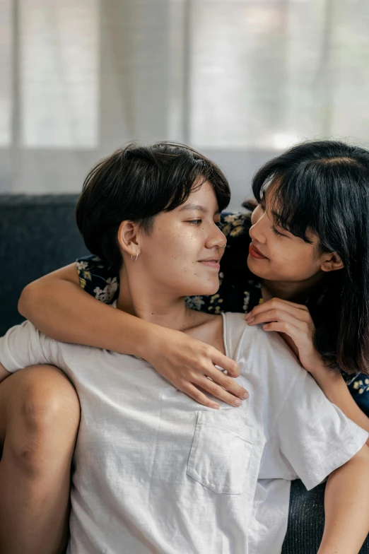 a woman sitting next to a man on a couch, trending on pexels, lesbian embrace, indonesia, woman holding another woman, korean woman