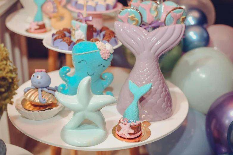 a table that has a bunch of cupcakes on it, a cartoon, trending on pexels, magical realism, mermaid tail, ceramic, chocolate, low quality photo