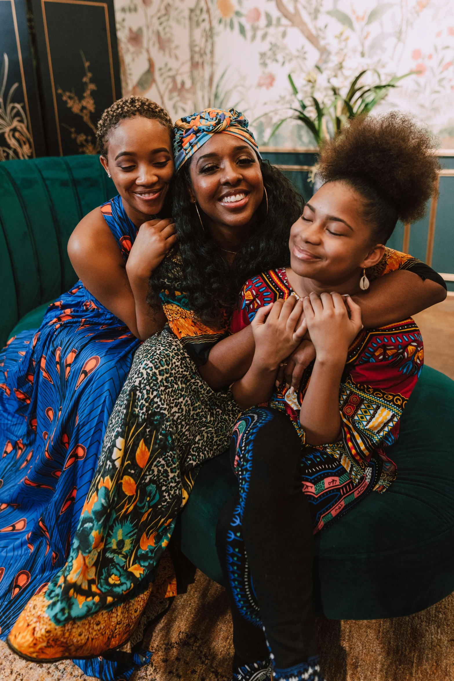 three women sitting on a bean bag in a living room, by Lily Delissa Joseph, trending on unsplash, afrofuturism, wearing an african dress, hugging each other, black teenage girl, patterned clothing