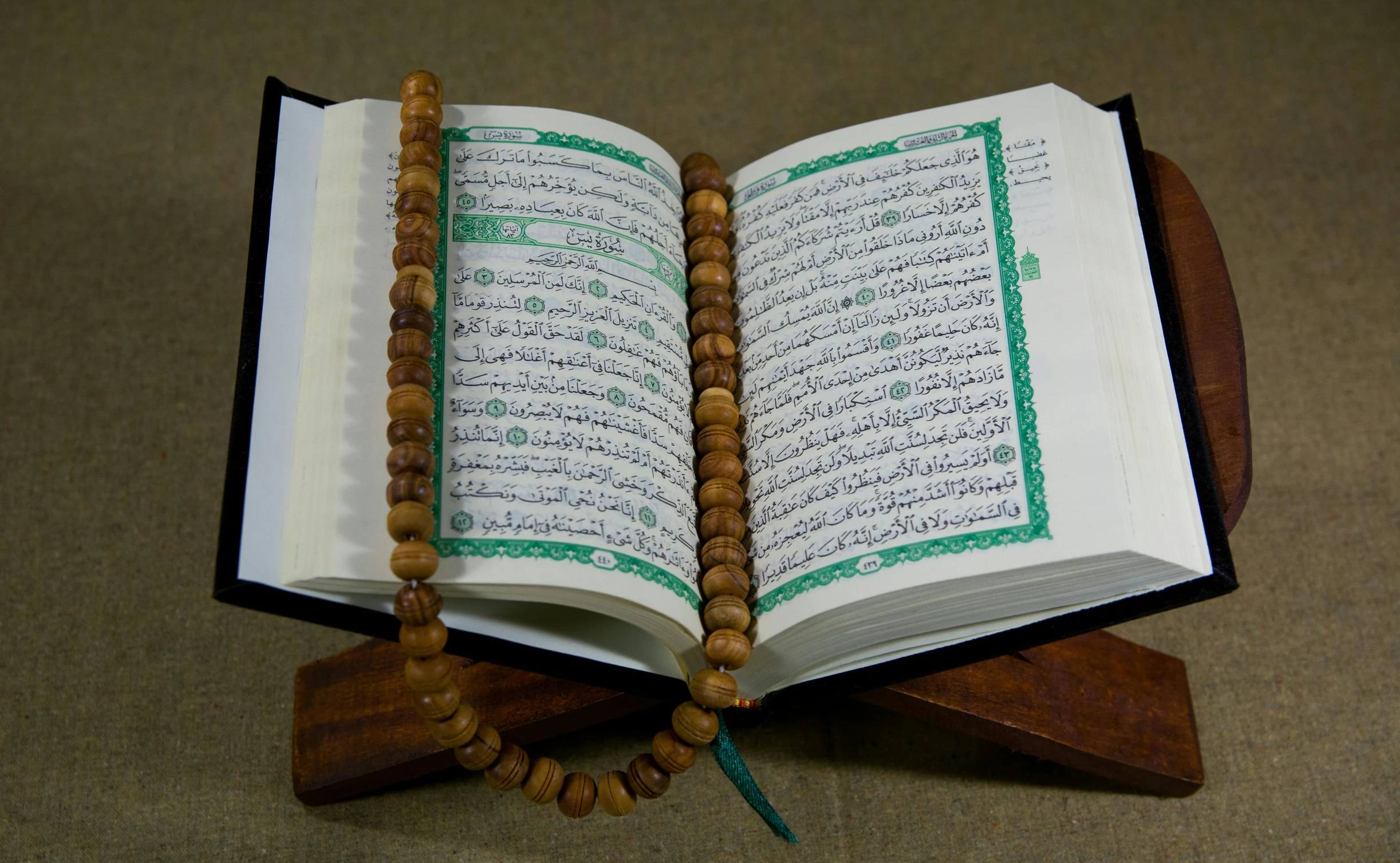 an open book sitting on top of a wooden stand, hurufiyya, fully decorated, handheld, very very precise