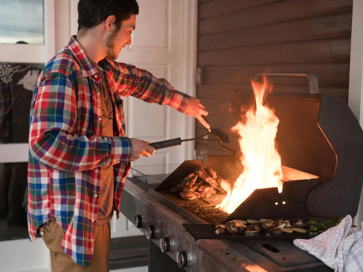 a man is cooking food on a grill, by Carey Morris, pexels, in front of a fireplace, blair armitage, torch lighting, college