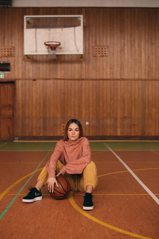 a woman sitting on a basketball court holding a basketball, by Christen Dalsgaard, highly upvoted, ocher, low quality photo, schools