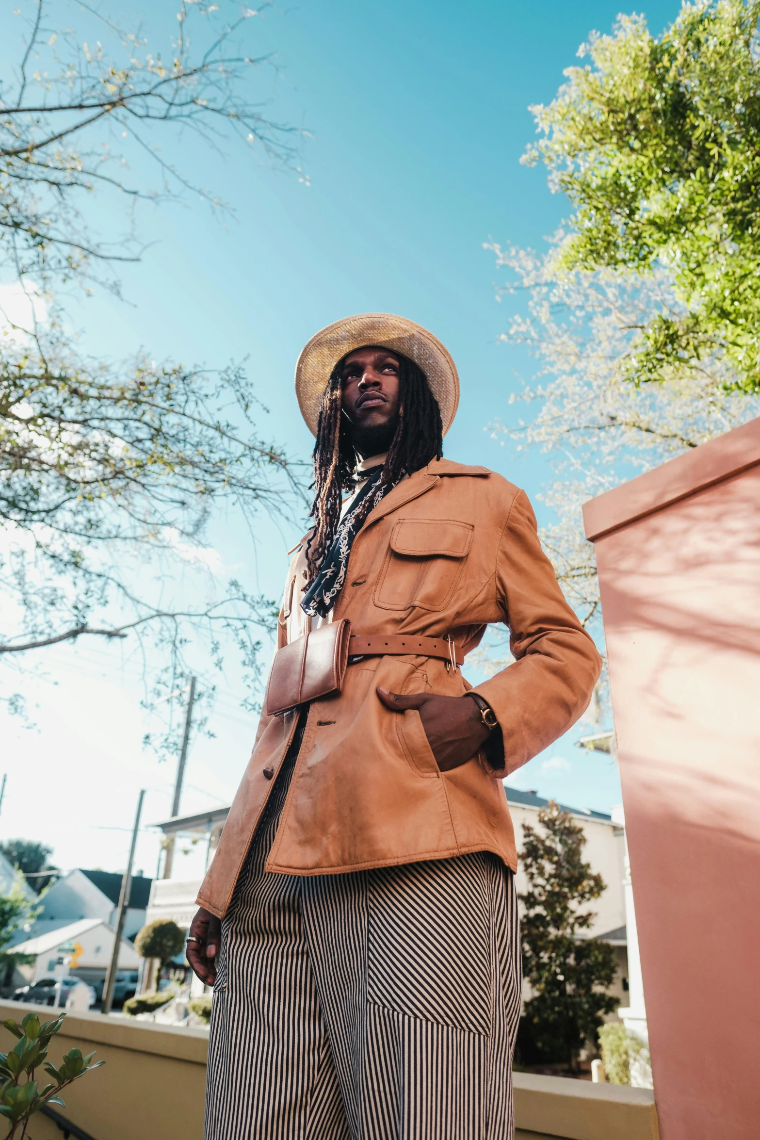 a man in a suit and hat posing for a picture, an album cover, trending on pexels, dreads, in savannah, light brown trenchcoat, uniform off - white sky