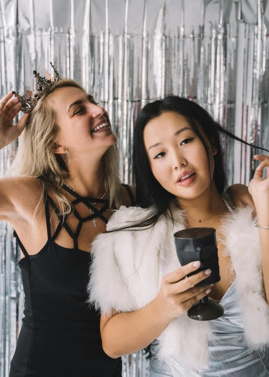 a couple of women standing next to each other, a polaroid photo, inspired by Wang Duo, trending on unsplash, happening, posing in leotard and tiara, new years eve, with curly black and silver hair, drinks