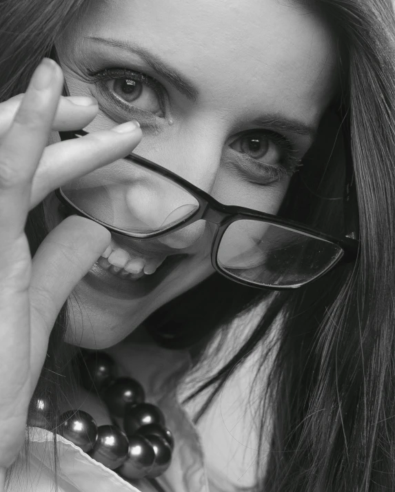a black and white photo of a woman wearing glasses, by Anita Malfatti, pexels contest winner, naughty smile, teasing smile, hands on face, smiling :: attractive