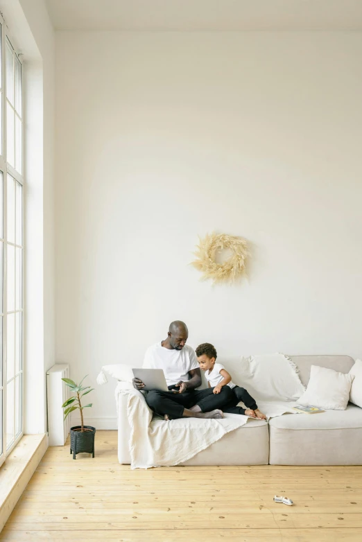 a man and a woman sitting on a couch in a living room, pexels contest winner, light and space, father with child, clean minimalist design, using a macbook, promo image