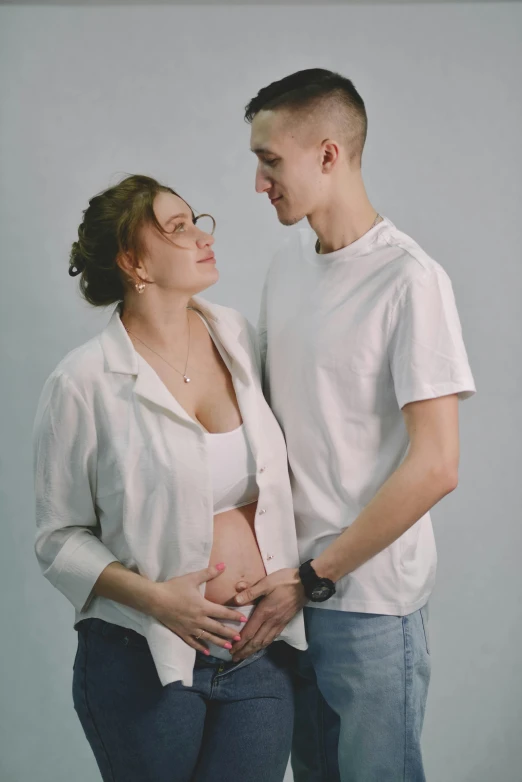 a man and a woman standing next to each other, a colorized photo, pexels contest winner, hyperrealism, pregnancy, russian girlfriend, dressed in a white t shirt, nursing