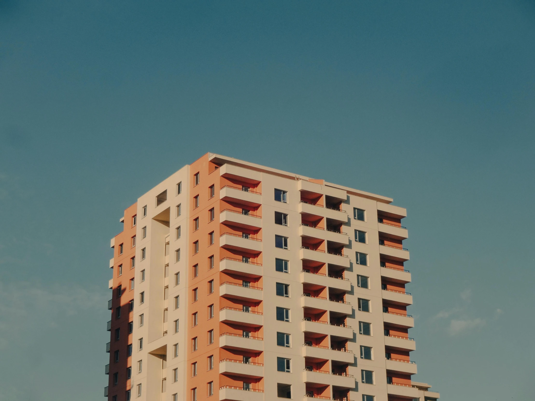 a tall building sitting on top of a lush green field, pexels contest winner, modernism, soviet apartment, orange and blue sky, minimalist photorealist, cascading highrise