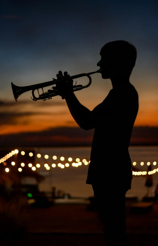 a silhouette of a man playing a trumpet, by Carey Morris, happening, evening lights, in a beachfront environment, profile image, medium close up shot