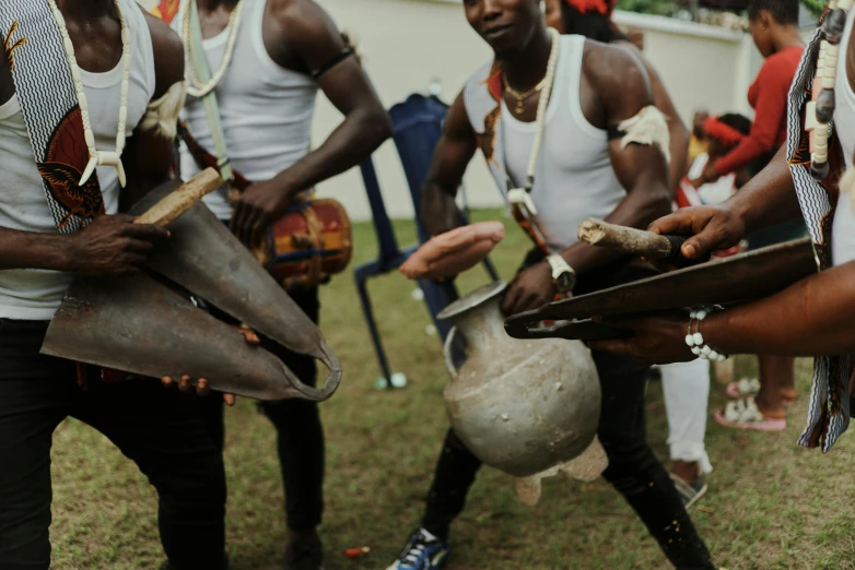 a group of men standing on top of a lush green field, an album cover, by Ingrida Kadaka, pexels contest winner, afrofuturism, holding maracas, white and orange breastplate, live performance, wearing ornate helmet