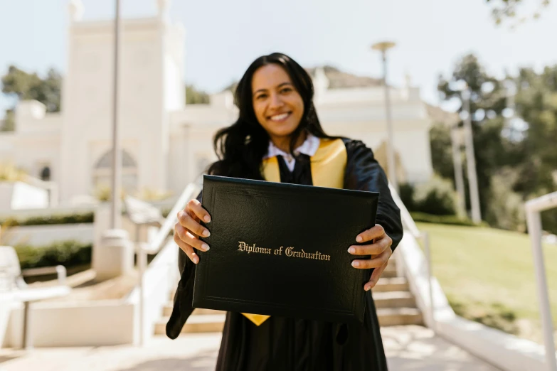 a woman in a graduation gown holding a diploma, a picture, by Nicolette Macnamara, pexels contest winner, holding a gold bag, wearing black clothes and cape, taliyah, smiling