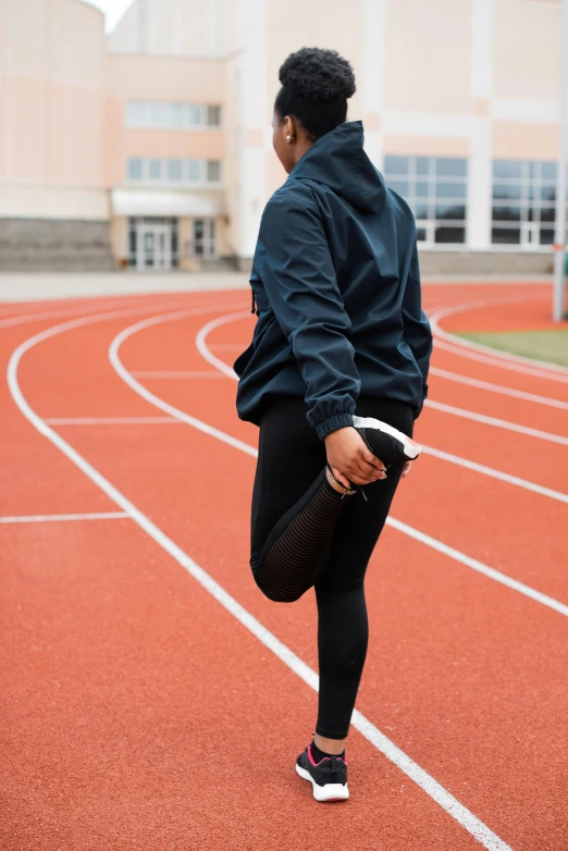 a woman standing on top of a running track, trending on unsplash, wearing jeans and a black hoodie, wearing black tight clothing, wearing jacket and skirt, knees weak