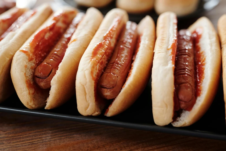 a black plate topped with hot dogs covered in ketchup, unsplash, bauhaus, square, けもの, steamed buns, getty images